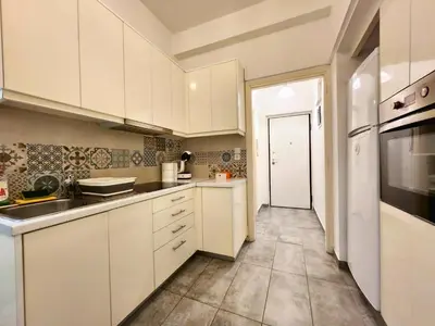 a kitchen with white cabinets and a sink and a refrigerator at Lycabettus Edge in Athens