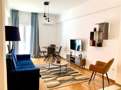 a living room with a blue couch and a table at Kallimarmaro 2-Bedroom Apartment in Athens