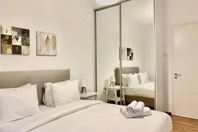 a bedroom with two beds with white sheets and a mirror at Kallimarmaro 2-Bedroom Apartment in Athens