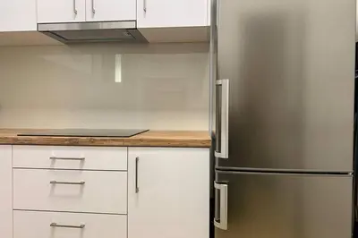 a kitchen with a refrigerator and white cabinets at Kallimarmaro 2-Bedroom Apartment in Athens