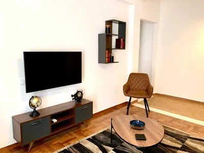 a living room with a television and a chair at Kallimarmaro 2-Bedroom Apartment in Athens