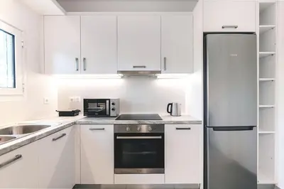 a kitchen with white cabinets and a stainless steel refrigerator at Boutique77 Luxury Apartment in Athens