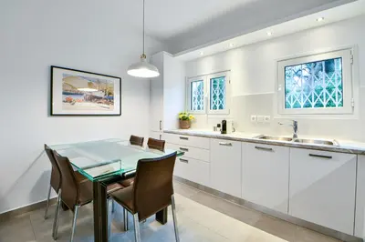 a kitchen with white cabinets and a table and chairs at Boutique77 Luxury Apartment in Athens