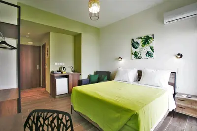 a hotel room with a green bed and a desk at Aethon Airport Project-FREE SHUTTLE by GK Properties in Markopoulo