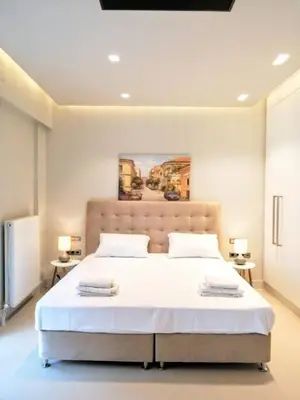a bedroom with a large white bed with two tables at Luxurious minimal apartment in Acropolis in Athens