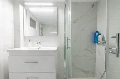a white bathroom with a sink and a shower at Victoria Diamond Suites Apartments in Athens