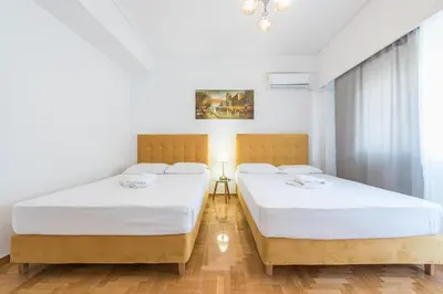 two beds in a room with white walls and wooden floors at Victoria Diamond Suites Apartments in Athens