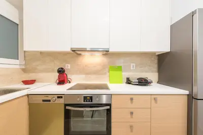 a kitchen with white cabinets and a stove top oven at Victoria Diamond Suites Apartments in Athens