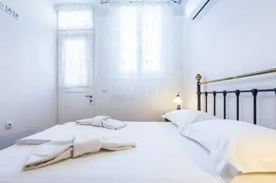 a white bedroom with a large bed with white sheets at Neoclassical apartment with 3 bedrooms in Piraeus in Piraeus