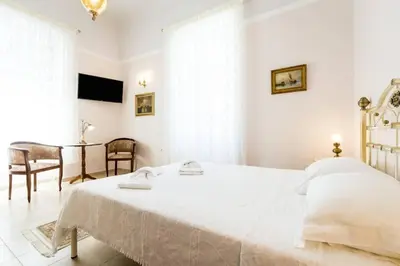 a white bedroom with a large bed and a table at Neoclassical flat with 2 bedrooms in Piraeus in Piraeus