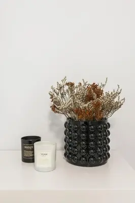 a black vase with a plant and a candle at Deluxe & Stylish 2BD Apartment in Pangrati by UPSTREET in Athens