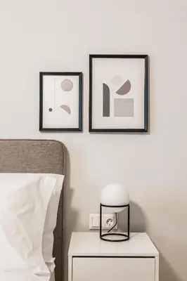 two framed pictures on a wall above a bed with a nightstand at Deluxe & Stylish 2BD Apartment in Pangrati by UPSTREET in Athens