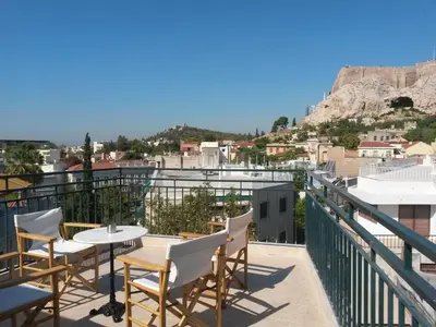 a balcony with tables and chairs and a view of a city at Adams Hotel in Athens