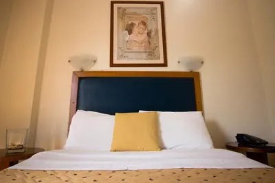 a bed with a blue headboard and a picture on the wall at Adams Hotel in Athens