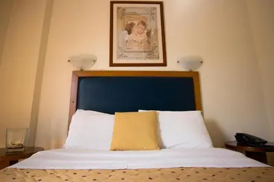 a bed with a blue headboard and a picture on the wall at Adams Hotel in Athens