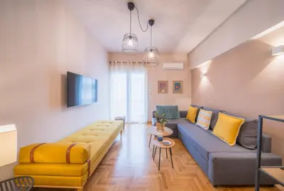 a living room with a blue couch and yellow accents at Brand new aprtm touching Acropolis in Athens