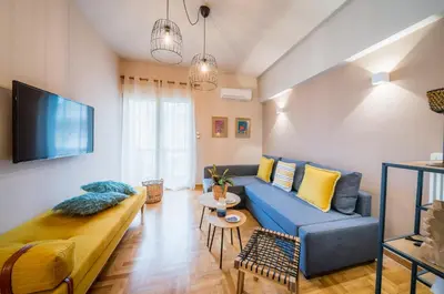a living room with a blue couch and a tv at Brand new aprtm touching Acropolis in Athens