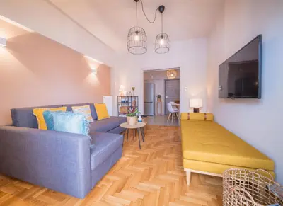 a living room with a blue couch and a flat screen tv at Brand new aprtm touching Acropolis in Athens