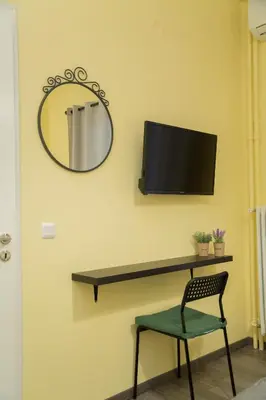 a mirror and a chair and a tv on a wall at Cozy renovated flat in Koukaki in Athens