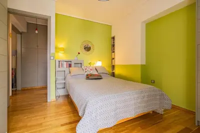 a bedroom with a bed with green walls and wooden floors at Lux clevercomfy appartmentthe center of Athens in Athens
