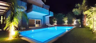 a swimming pool in front of a house at night at Unique Villa Melia Lagonisi in Kalívia Thorikoú