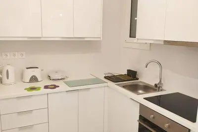 a white kitchen with a sink and white cabinets at Ilisos garden apartment in Athens