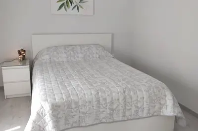 a bed with a white comforter and a side table at Ilisos garden apartment in Athens
