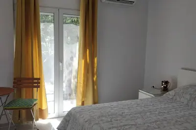 a bedroom with a bed and a window with yellow curtains at Ilisos garden apartment in Athens