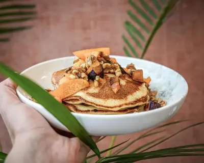 a person holding a bowl of pancakes with nuts at The Marblous Athens in Athens
