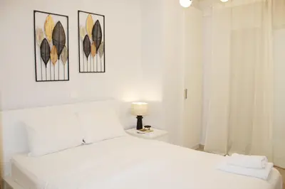 a bedroom with a white bed with three pictures on the wall at ARIS Piraeus Marina in Piraeus