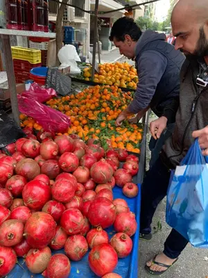 two men looking at a display of apples at a market at ARIS Piraeus Marina in Piraeus