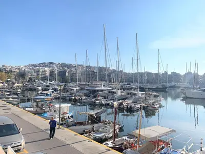 a man standing on a dock with boats in a marina at ARIS Piraeus Marina in Piraeus