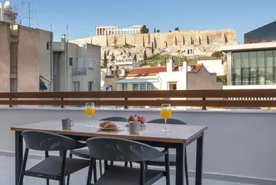 a table with two glasses of orange juice on a balcony at Acropolis Golden Suites by GHH in Athens