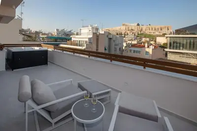 a balcony with a couch and a table and a tv at Acropolis Golden Suites by GHH in Athens