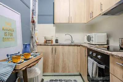 a small kitchen with wooden cabinets and a sink at Cozy in Athens Koukaki in Athens