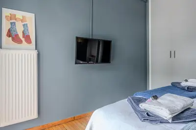 a bedroom with a tv and a bed with blue walls at Cozy in Athens Koukaki in Athens