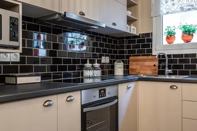 a kitchen with white cabinets and black tiles on the wall at Absolute Athens XI in Athens