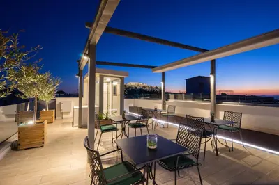 a rooftop patio with tables and chairs at night at Hestia - Romvis 9 in Athens