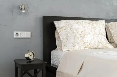 a bed with a pillow and a clock on a table at Elegant Light Two Bedroom Apartment in City Center in Athens