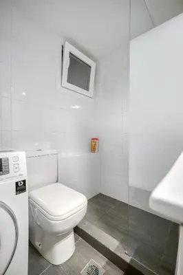 a white bathroom with a toilet and a tv at Elegant Light Two Bedroom Apartment in City Center in Athens