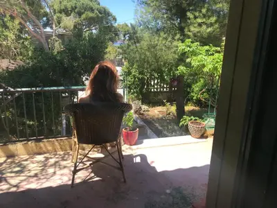 a woman sitting in a chair on a porch at Kokos Traditional Family House in Sounio