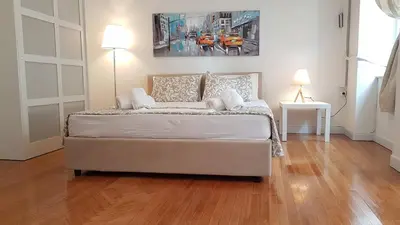a bed in a room with a wooden floor at Ionian Apartment- Athens Center, 6 BD, 2.5 BATH in Athens