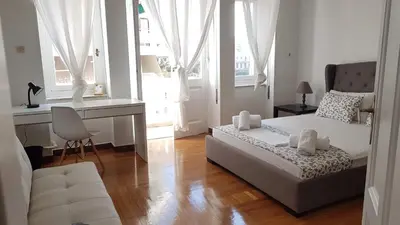 a bedroom with a bed and a desk and windows at Ionian Apartment- Athens Center, 6 BD, 2.5 BATH in Athens