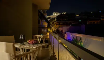 a balcony with a table and a view of a city at night at Acropolis Grand Apartment in Athens