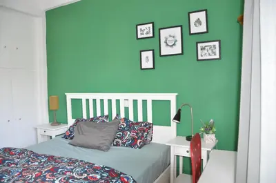 a bedroom with green walls and a bed with pillows at Sunny Apartment with view in Athens