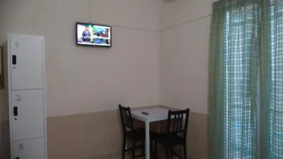 a room with a table and two chairs and a tv on the wall at SAN REMO HOSTEL in Athens