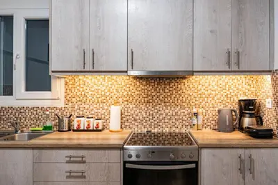 a kitchen with white cabinets and a stove top oven at Apartment @Katehaki Metro in Athens