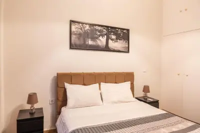 a bedroom with a bed with white sheets and two lamps at Apartment @Katehaki Metro in Athens
