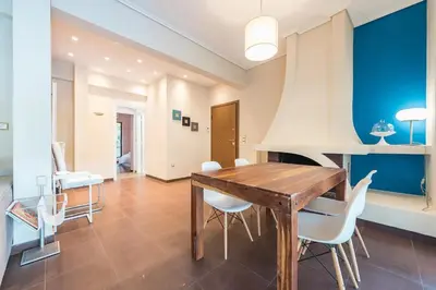 a dining room with a wooden table and white chairs at Glyfada Glass-Walled Designed Apt 1Gbps in Athens
