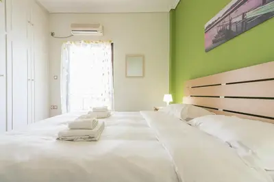 a large white bed in a room with a green wall at Glyfada Glass-Walled Designed Apt 1Gbps in Athens